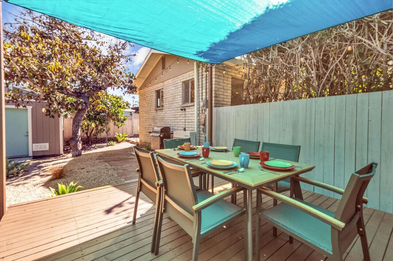 An outdoor patio with a table set for four, surrounded by chairs.