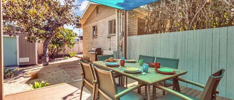 An outdoor patio with a table set for four, surrounded by chairs.