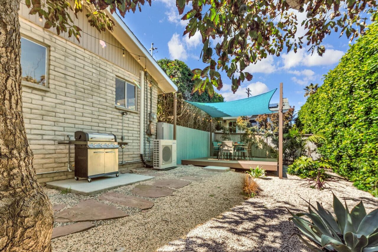 Un jardin avec un barbecue, un espace salon extérieur et une pergola.