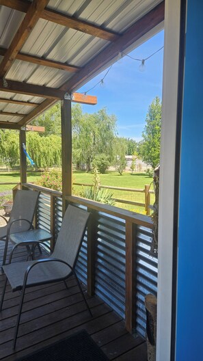 A covered outdoor seating area with chairs and a view of a grassy yard.