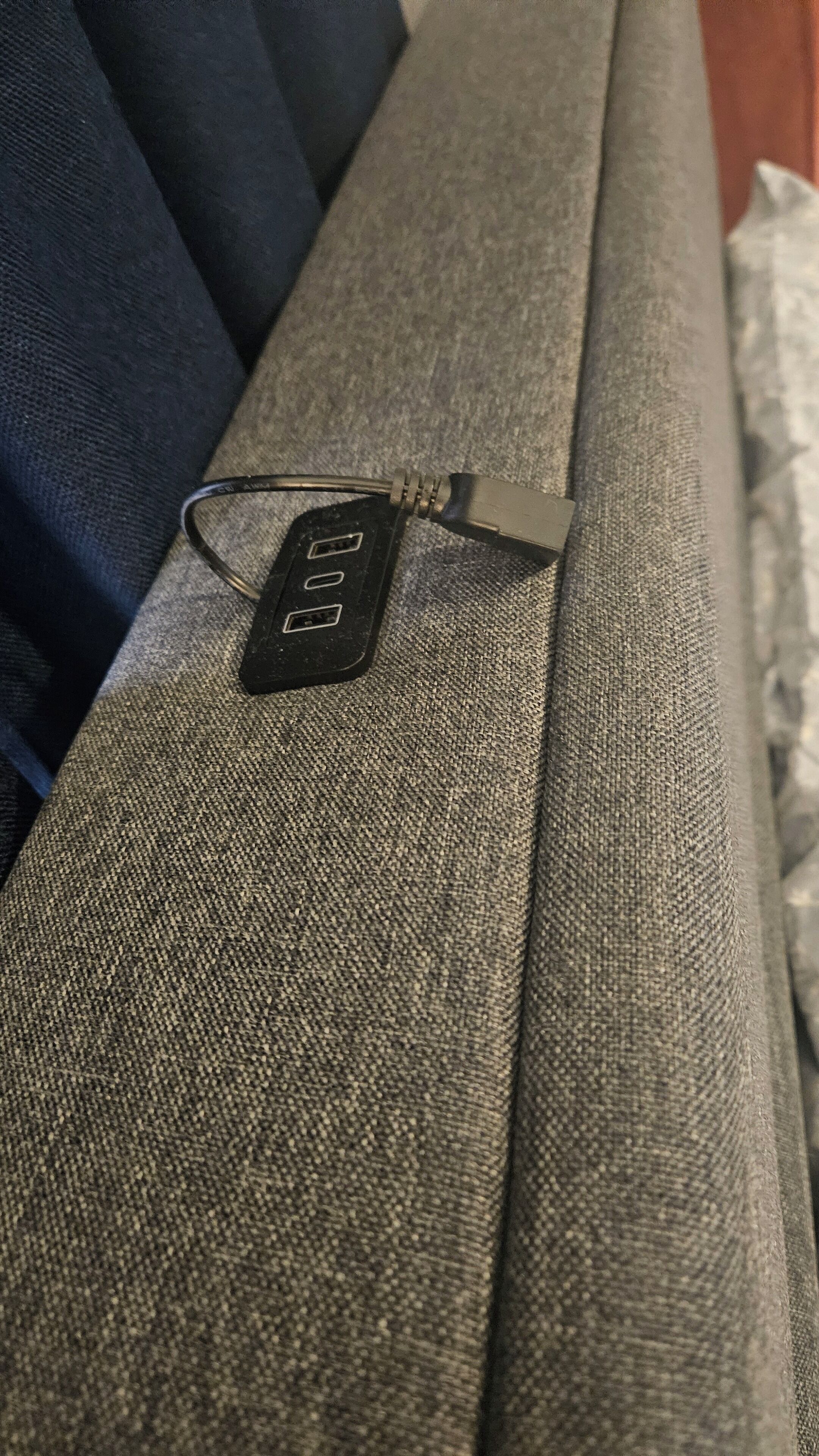 Een stroomadapter met een USB-poort op een gestructureerd stoffen oppervlak.