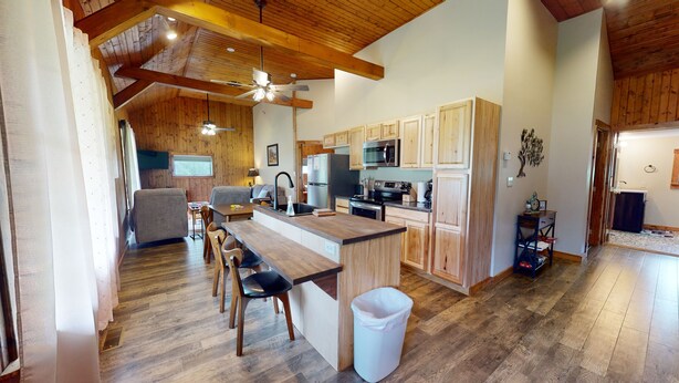 A spacious kitchen with wooden cabinets, a central island, and a dining area with chairs. - Escape to Pine Creek and PA Grand Canyon stay at Willow Cabin (Gaines)