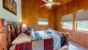 A wooden cabin bedroom with a bed, a ceiling fan, and windows. - Escape to Pine Creek and PA Grand Canyon stay at Willow Cabin (Gaines)