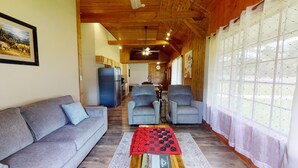 A cozy living room with a sofa, two armchairs, a red and black checkered table, and a wooden ceiling. - Escape to Pine Creek and PA Grand Canyon stay at Willow Cabin (Gaines)