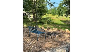 A bench in a natural setting with a gravel path, surrounded by rocks and trees. - Cozy Tiny Home Cabin Near Lake Greeson & Kirby Landing – Pet-Friendly! (Kirby)