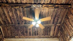 Een plafond met een houten structuur en een centrale plafondventilator.