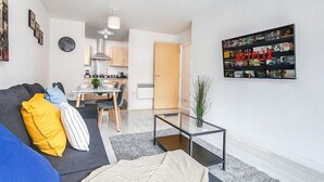 Un salon moderne avec un canapé, une table basse et une œuvre d’art accrochée au mur.