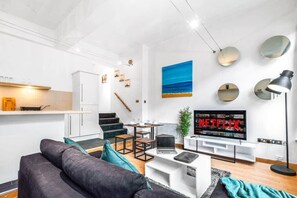 Un salon moderne comprenant un canapé, une table basse, un téléviseur et un escalier menant à la cuisine.