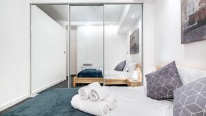 Ett modernt hotellrum med en säng, en garderob och en tavla på väggen.
