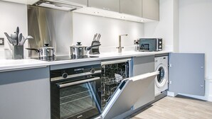 Eine moderne Küche mit integrierten Geräten, darunter eine Spülmaschine, ein Backofen und eine Mikrowelle, sowie eine graue Waschmaschine.
