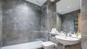 Une salle de bain moderne avec une douche à parois de verre, une baignoire blanche et un lavabo équipé de produits de toilette.