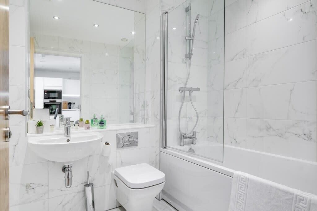 A modern bathroom with a white sink, toilet, and shower.