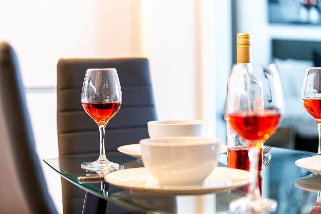 A dining table with wine glasses, a bottle, and white bowls.