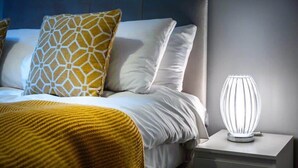 Uma cama bem arrumada com travesseiro estampado e mesa de cabeceira com abajur moderno.
