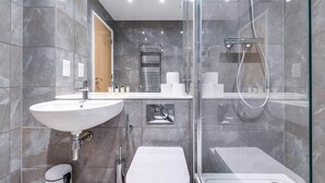 Un baño moderno con ducha acristalada, un lavabo blanco y un inodoro.