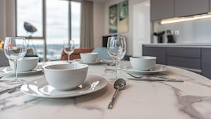 A dining table set with white bowls and wine glasses, a spoon, and cutlery.
