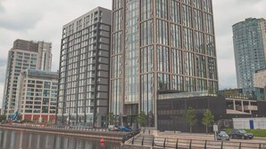 A modern high-rise building with a glass facade, situated near a body of water with a floating orange buoy. - The Lexington III 2BDR | Games Room | Netflix (Merseyside)
