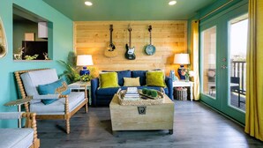 A cozy living room with a blue sofa, wooden coffee table, and a wall adorned with guitars.