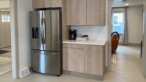 Una cocina moderna con armarios de madera, un refrigerador de acero inoxidable y una cafetera sobre la encimera.