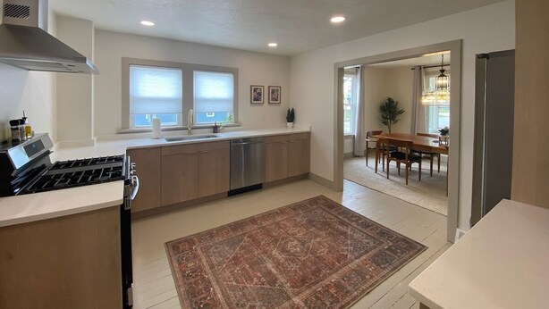 Una cocina moderna con estufa a gas, lavavajillas y un comedor con mesa y sillas.