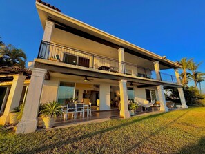 A two-story building with a balcony, potted plants, and a grassy lawn. - Villa Familiar Frente al mar (Cruz de Huanacaxtle)