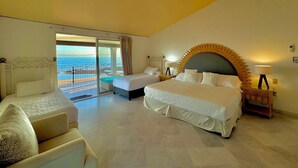 A bedroom with a large bed, a smaller bed, a sofa, and a ceiling fan. There is a view of the ocean through a sliding door. - Villa Familiar Frente al mar (Cruz de Huanacaxtle)