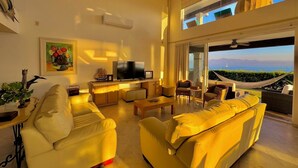 A spacious living room with a large sofa, a television, and a view of the sea through a balcony. - Villa Familiar Frente al mar (Cruz de Huanacaxtle)