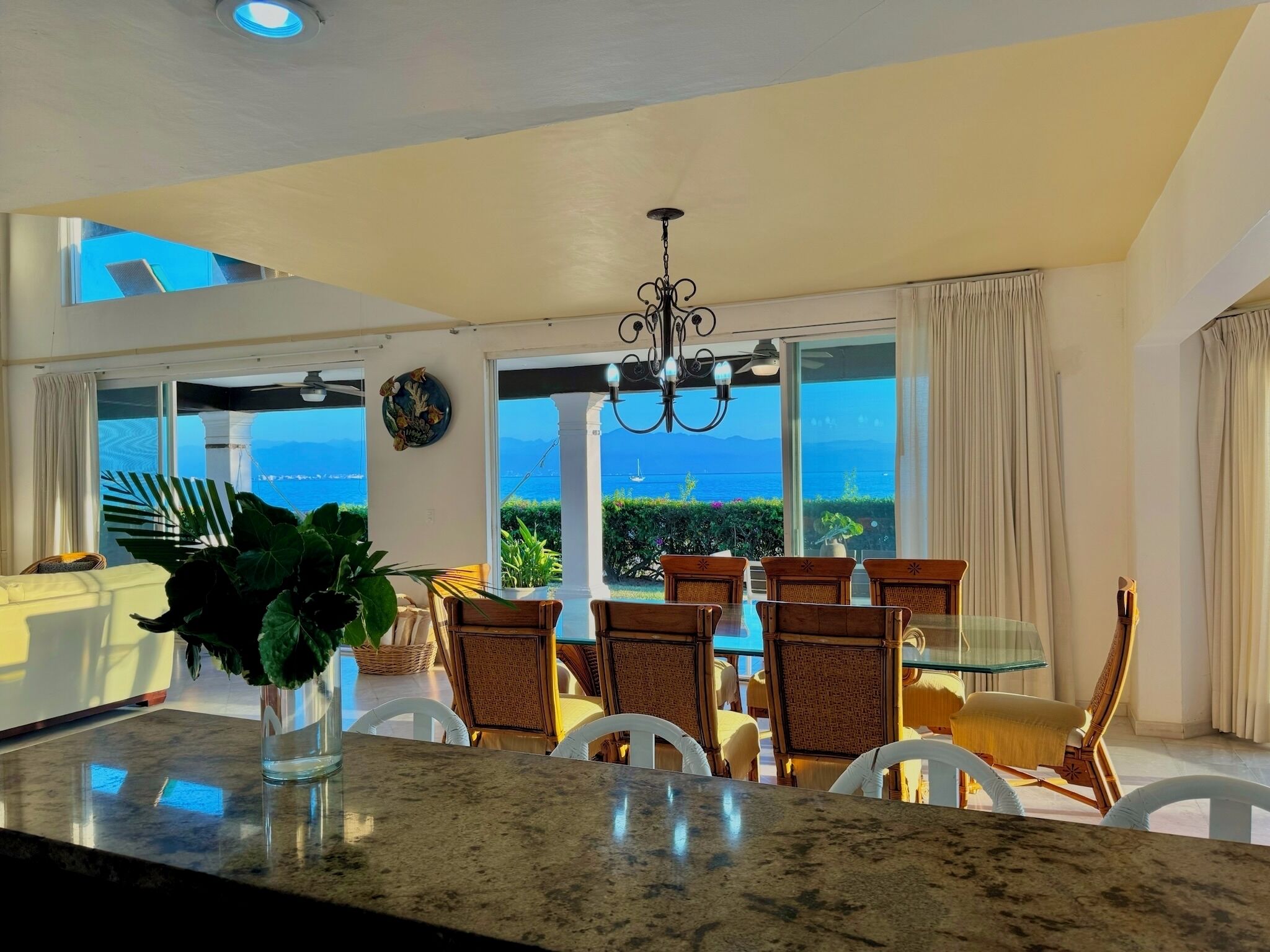 A dining area with a view of the sea, a chandelier, and a large window.