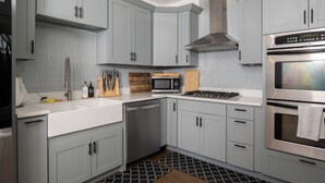Una cocina moderna con gabinetes grises, electrodomésticos de acero inoxidable y un tapete con estampado blanco y negro.