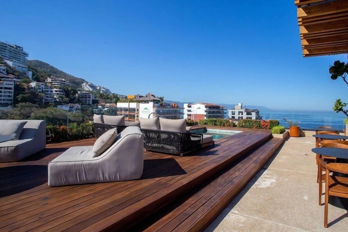 Terraço no telhado com área de estar ao ar livre, piscina e vista para o oceano e edifícios na colina.