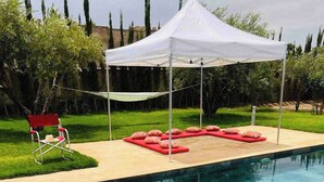 A swimming pool with a white canopy, red lounge chairs, and a red chair. - Private Villa With Swimming Pool in Lalla Takerkousst-marrakech (Lalla Takarkoust)