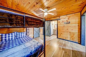 A wooden cabin interior with a bunk bed, a ceiling fan, and a kitchen area visible through an open door. - Hot Tub - Mountain View - Fire Pit - Gas Grill - Comfy Beds - Pet Friendly (Ellijay)