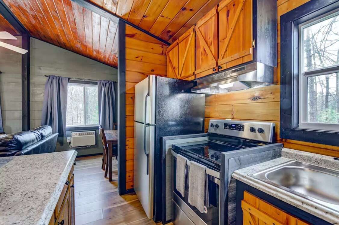 A compact kitchen with wooden cabinets, a refrigerator, stove, and a sink.