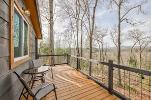 A wooden deck with a table and chairs, overlooking a forested landscape. - Hot Tub - Mountain View - Fire Pit - Gas Grill - Comfy Beds - Pet Friendly (Ellijay)