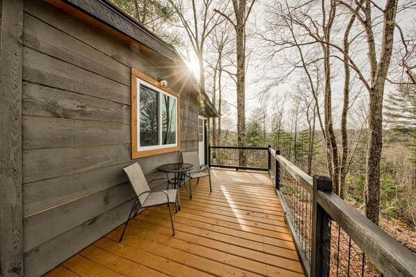 A wooden deck with a table and chairs, surrounded by trees.