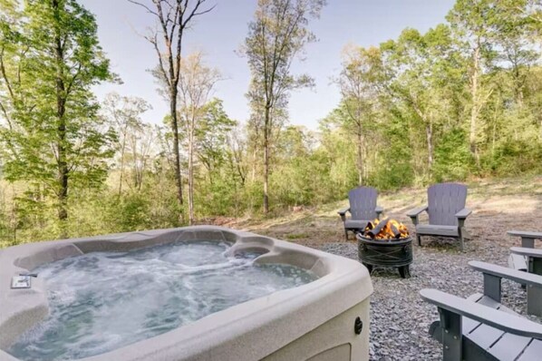 A hot tub surrounded by outdoor seating and a fire pit in a forested area. - Hot Tub - Mountain View - Fire Pit - Gas Grill - Comfy Beds - Pet Friendly (Ellijay)