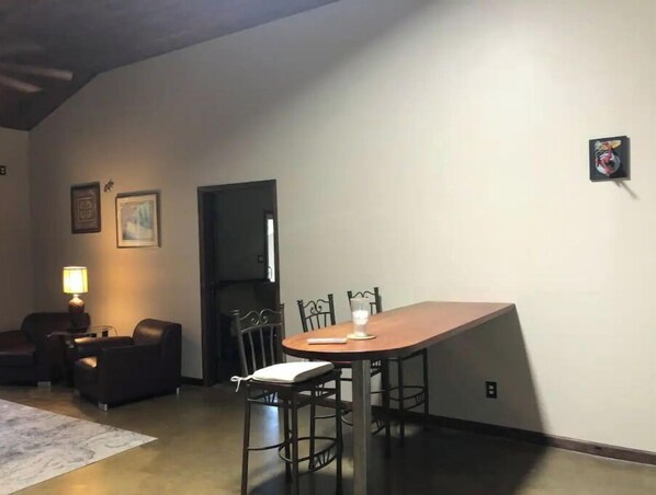 A dining area with a wooden table and metal chairs, a sofa, a lamp, and a door.