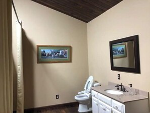 A bathroom with a toilet, sink, and a framed picture on the wall.