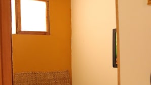 Une petite chambre à coucher, chaleureuse et accueillante, avec un lit simple, une fenêtre et un plafond en bois.
