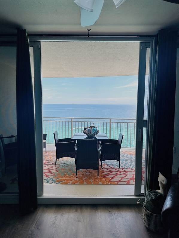Una habitación con vista al mar a través de un ventanal, una mesa con sillas y una alfombra estampada.