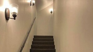 Portaat, joiden askelmat on päällystetty matolla ja joissa on kaide. Portaita reunustavat seinään kiinnitetyt valaisimet.