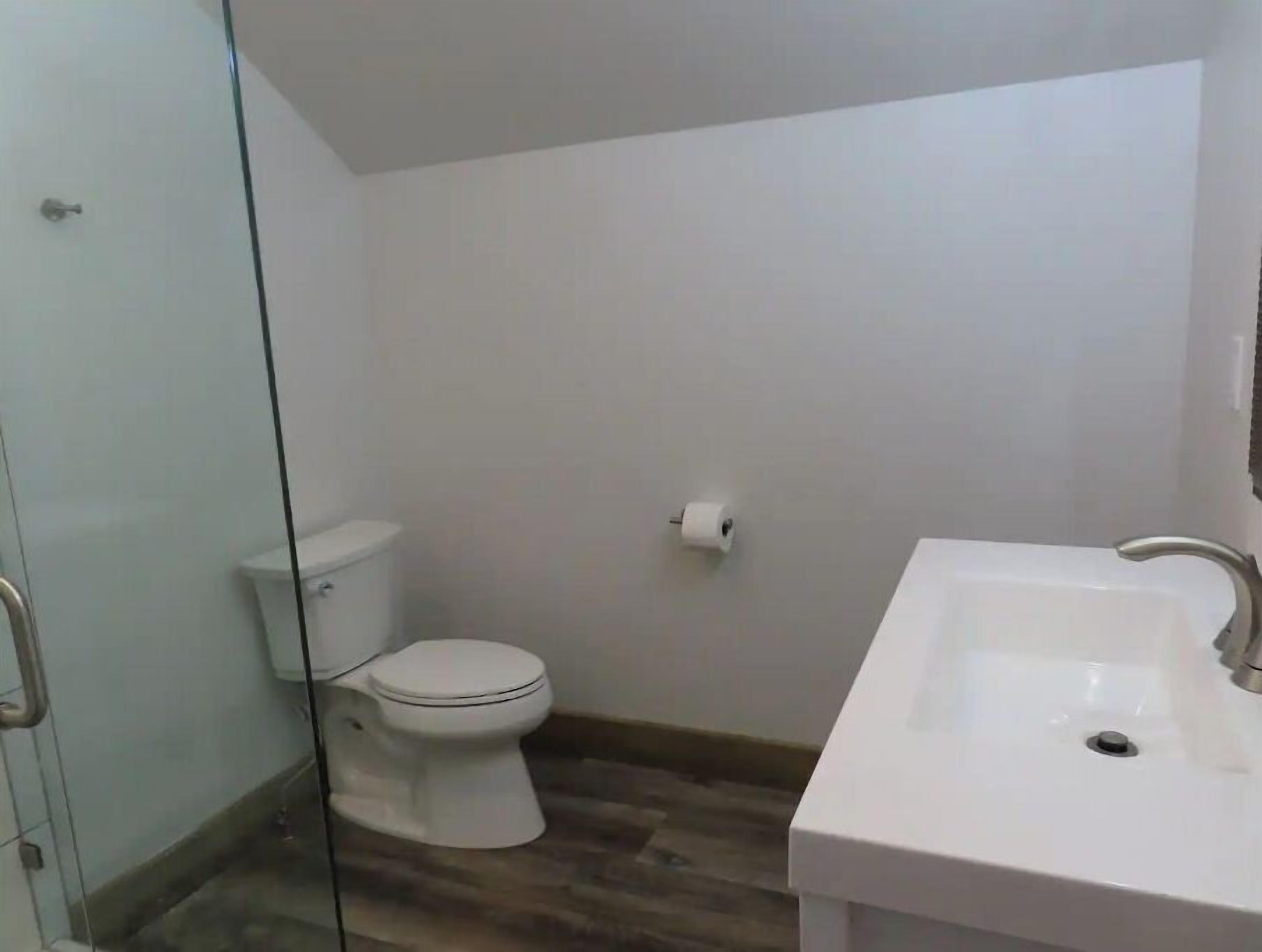 Ein Badezimmer mit Toilette, Waschbecken und einer Duschkabine aus Glas.