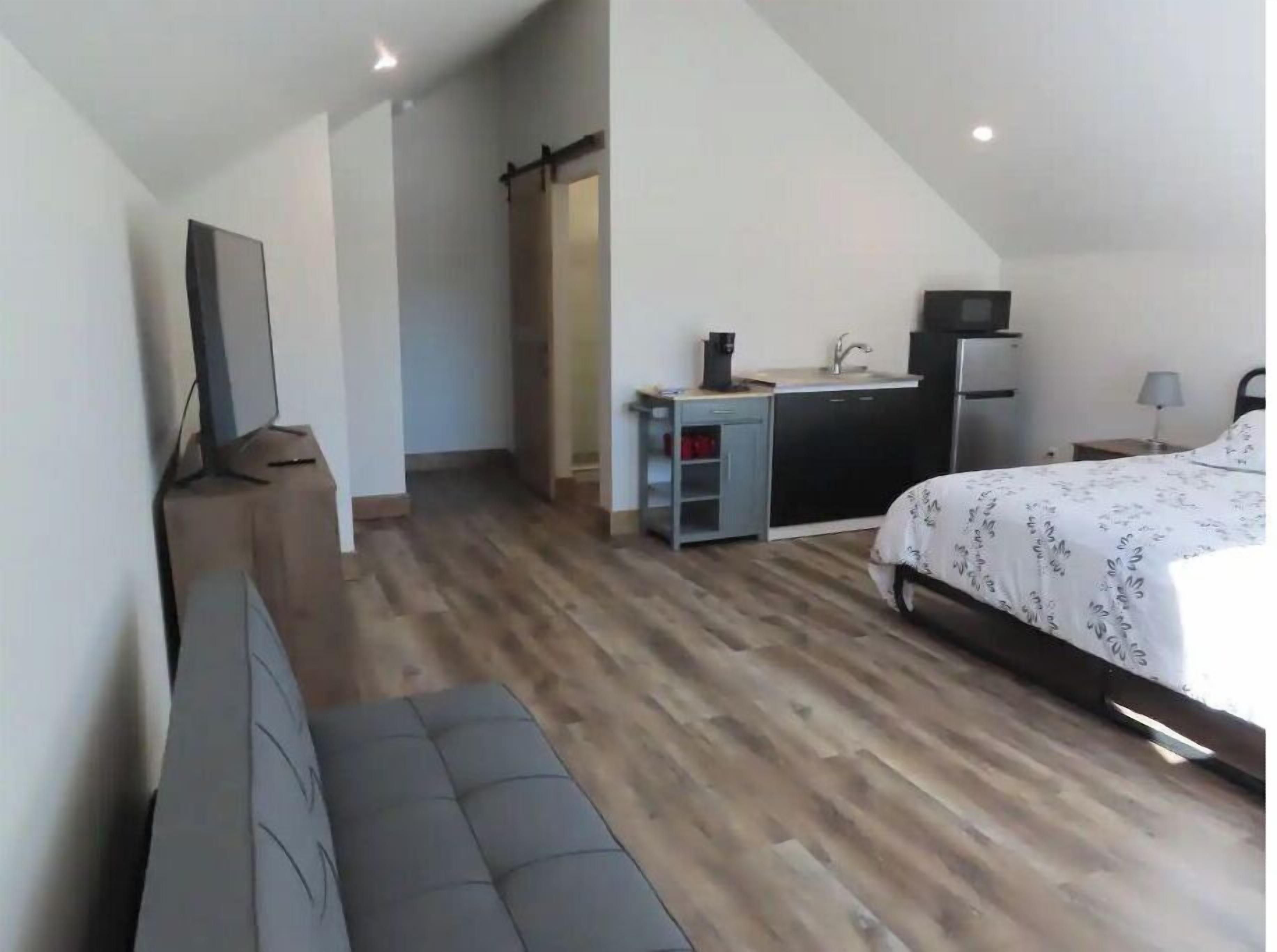 Ein modernes Schlafzimmer mit Bett, Schreibtisch und einer Küchenzeile.