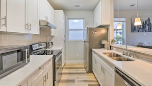 A modern kitchen with white cabinets, stainless steel appliances, and a large window. - Walk to TCU: Fort Worth Retreat w/ Balcony! (Fort Worth)
