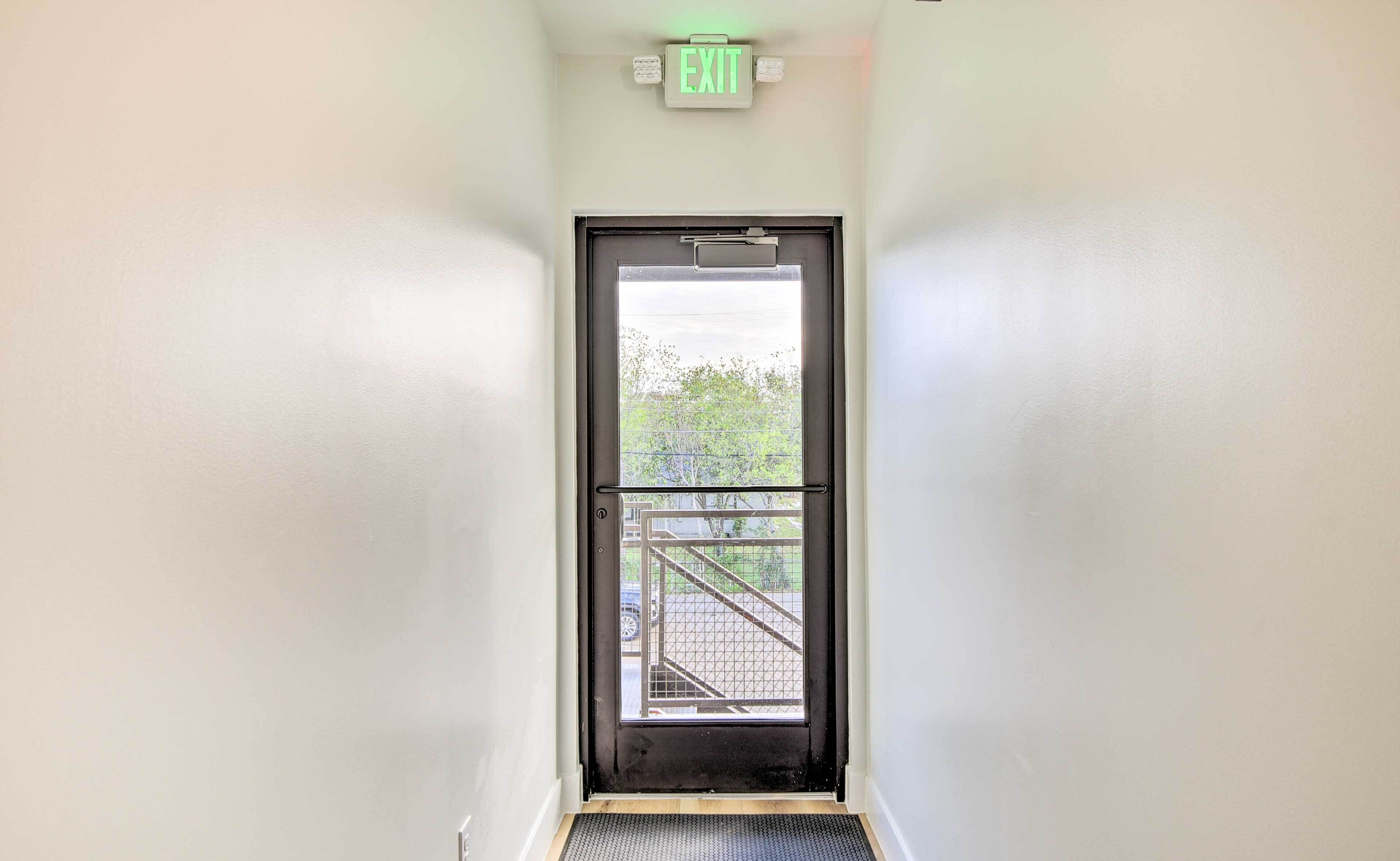 A narrow hallway with a door leading to an outdoor area.