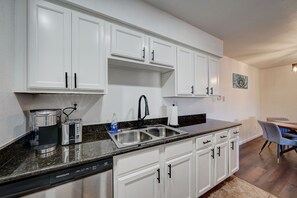 Enjoy cooking and dining in this well-equipped kitchen with a dishwasher, coffee maker, and toaster, adjacent to a dining area with a table and chairs.