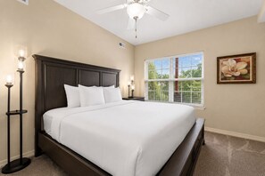 A bedroom with a large bed, a ceiling fan, a window with blinds, and a painting on the wall. - Spacious 3BR/2.5BA Townhouse • Near Hwy 76 Strip • Balcony, WiFi (Branson)