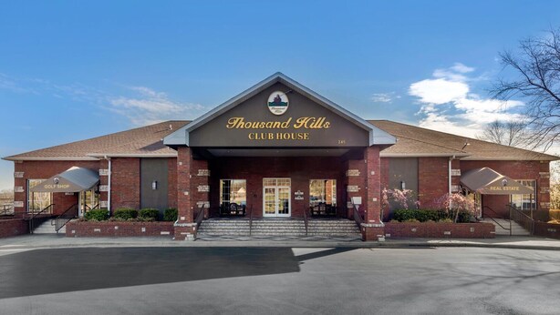 Un edificio de ladrillo con un letrero que dice “Thousand Hills CLUBHOUSE” y “GOLF SHOP” a cada lado.
