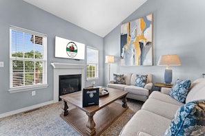 A living room with a fireplace, a sofa set, a coffee table, and a painting on the wall. - Spacious 3BR/2.5BA Townhouse • Near Hwy 76 Strip • Balcony, WiFi (Branson)