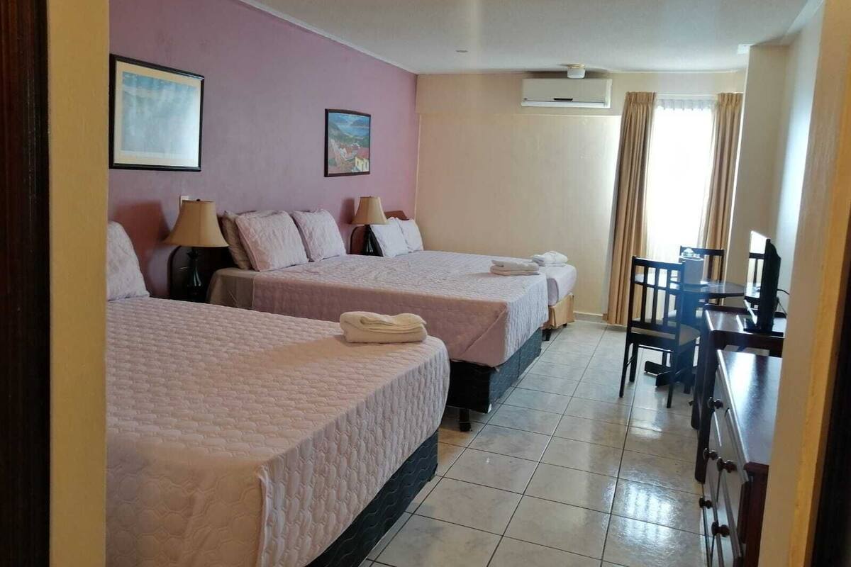 Habitación de hotel con dos camas, un escritorio y una silla.